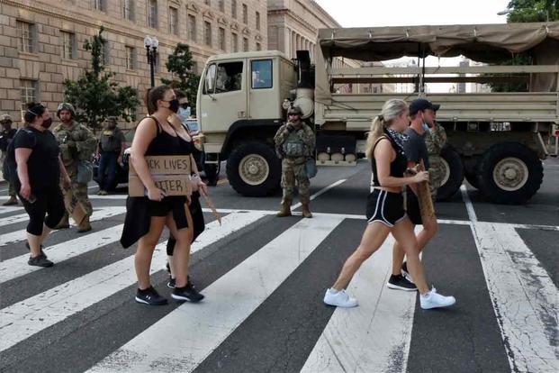 Demonstrators pass National Guard soldiers at a roadblock in Washington, D.C.