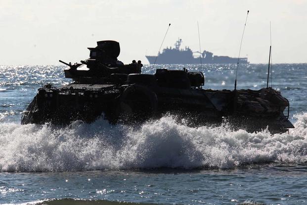 An amphibious assault vehicle drives onto the beach.