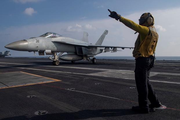 A sailor directs an F/A-18E Super Hornet on the flight deck of the USS Nimitz. 