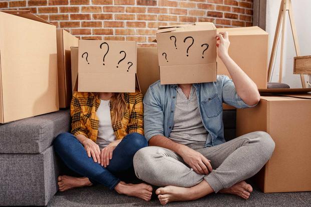 A couple sits with boxes on their heads.