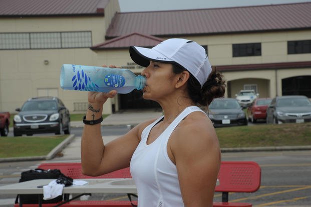 Woman drinks water after workout to stay hydrated.