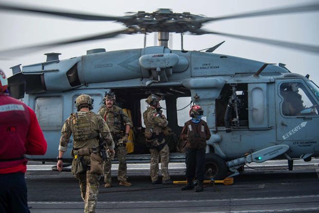 U.S. Navy sailors board an MH-60S Seahawk helicopter on the flight deck of USS Ronald Reagan.