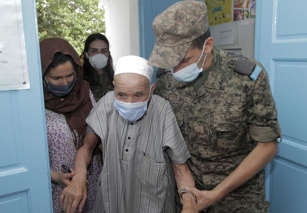 A soldier helps an elderly man to enter the vaccination center in Kesra July 13, 2021.