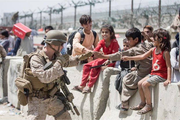 A U.S. Marine Corps Marine with Special Purpose MAGTF - Crisis Response - Central Command plays with children at Hamid Karzai International Airport in Kabul, Afghanistan.