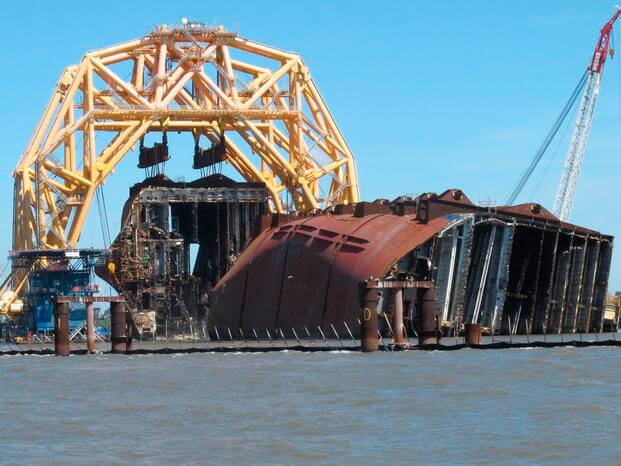 A towering crane pulls the engine room section away from the remains of the capsized cargo ship Golden Ray.