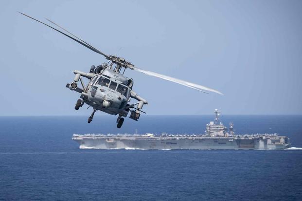 An MH-60S Sea Hawk helicopter flies near the USS Harry S. Truman