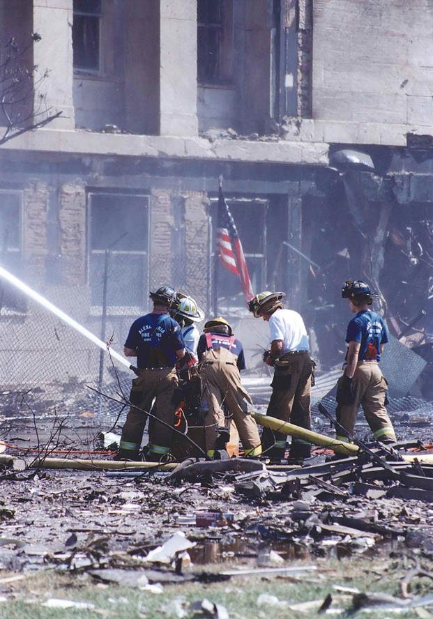 Fire crews work while standing amidst piles of debris, 11 September 2001.