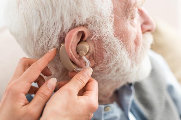 Adobe Woman Helping Man with Hearing Aid