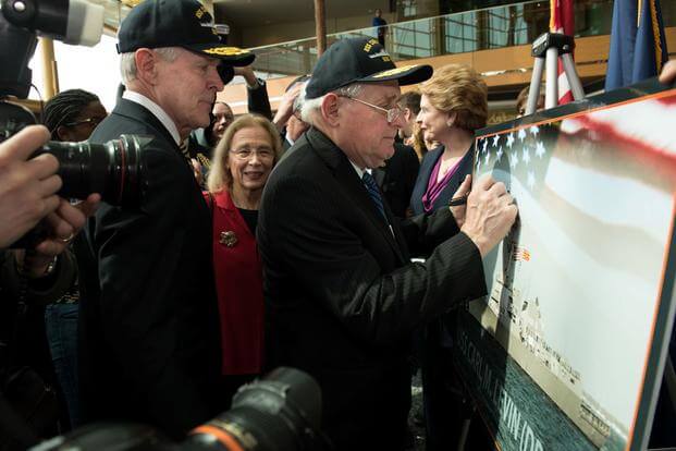 Former U.S. Senator Carl M. Levin signs a graphic representation of the USS Carl M. Levin (DDG 120).