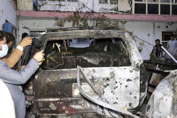 Afghan journalists take a photos of destroyed vehicle inside a house