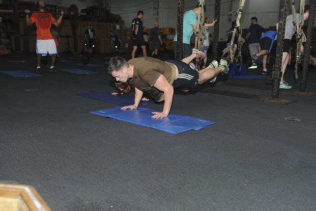 A sailor does TRX push-ups during a functional fitness class.