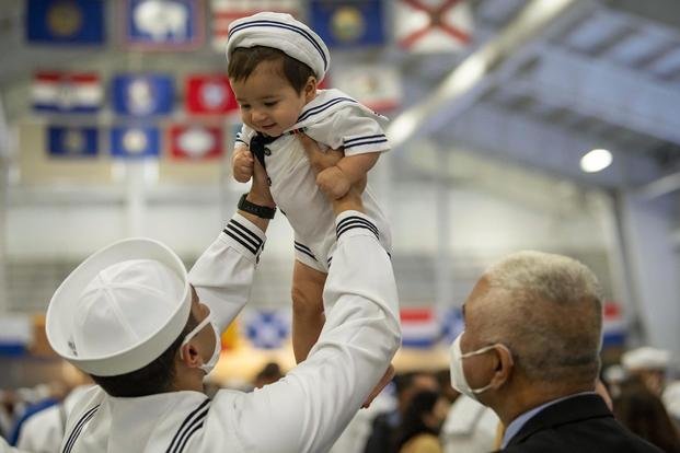 Navy Seaman Dominick Mazuera lifts his son Mateo in the air after seeing him for the first time since graduating from Recruit Training Command in Great Lakes, Ill.
