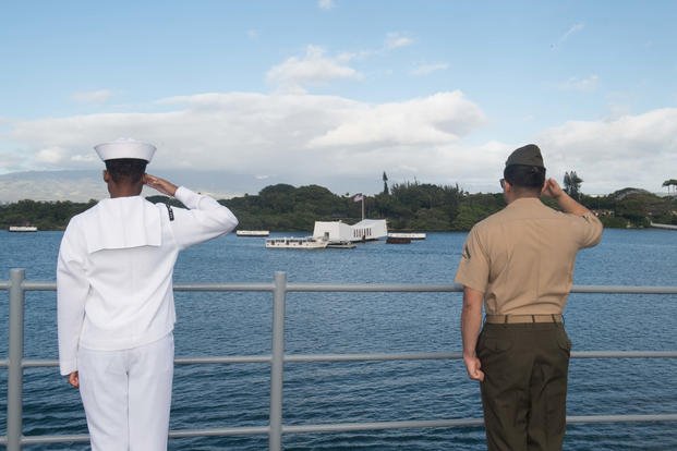 A sailor and a Marine render honors as the ship passes the USS Arizona memorial