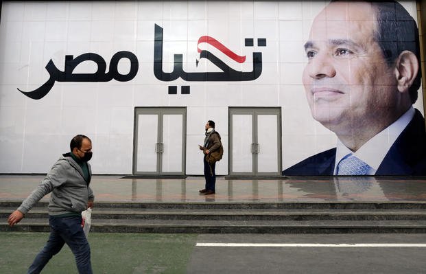 A man walks in front of a billboard for Egyptian President Abdel-Fattah el-Sissi.