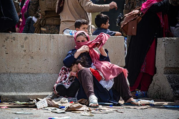 A woman and children wait for transportation to the terminal at Hamid Karzai International Airport