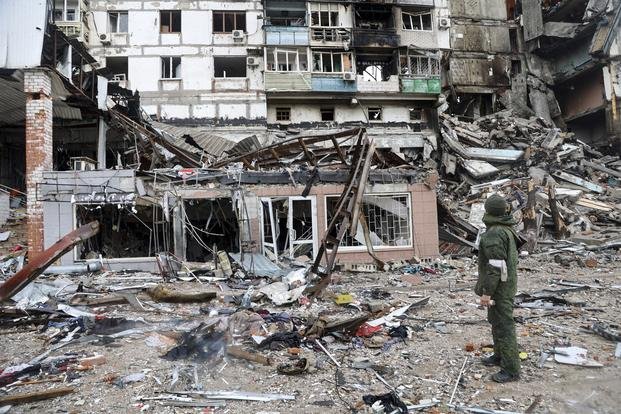 A serviceman stands at a building damaged during fighting in Mariupol, Ukraine.
