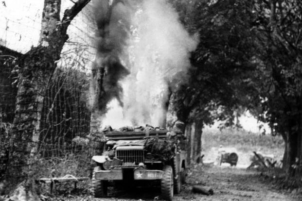 Pulled up by the side of a country roA half-track vehicle burns by the side of a road near St. Lo, France.