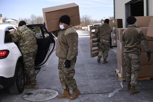 Members of the Connecticut National Guard load COVID-19 test kits into vehicles.