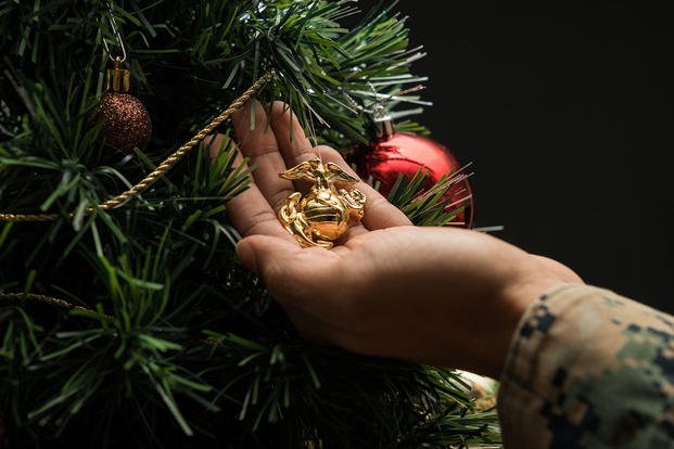 A Marine hangs an eagle, globe and anchor on a Christmas tree at Camp Hansen, Okinawa, Japan