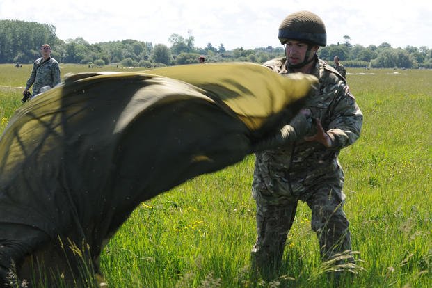 A British Army paratrooper gathers his parachute after landing in Picauville, France, during an event commemorating the 70th anniversary of D-Day.