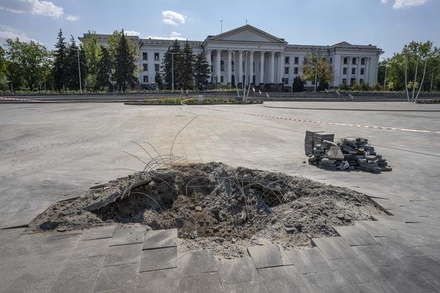crater in the aftermath of a Russian missile strike, in front of the city council hall building