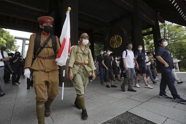 Visitors in Imperial army uniforms enter Yasukuni Shrine to honor Japan's war dead.