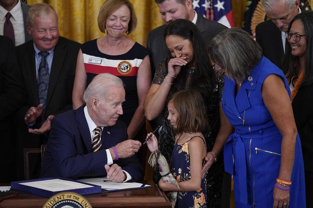 President Joe Biden gives the pen he used to sign the PACT Act of 2022 to Brielle Robinson, daughter of Sgt. 1st Class Heath Robinson, who died of cancer two years ago, during a ceremony in the East Room of the White House.