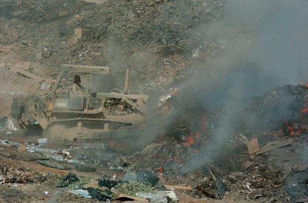 Sgt. Richard Ganske, 84th Combat Engineer Battalion uses a bulldozer to manuever refuse into the burn pit; sorting and burning it to manage LSA Anacondas sanitation requirements.