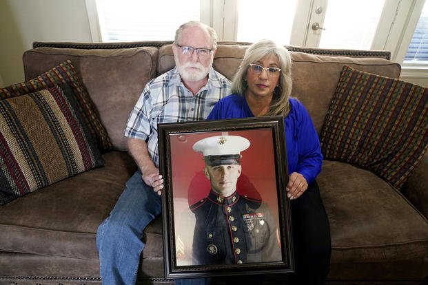 Joey and Paula Reed pose for a photo with a portrait of their son, Marine veteran and Russian prisoner Trevor Reed, at their home in Fort Worth, Texas.