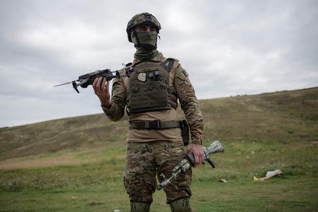 Ukrainian military volunteer soldier holds up a drone. 