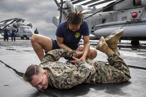 A sailor simulates handcuffing a suspect after being sprayed by pepper spray.