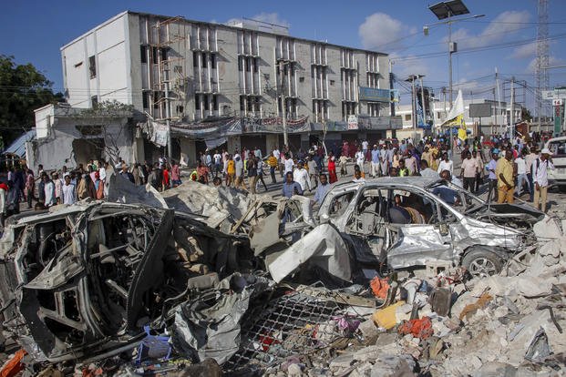 People walk amidst destruction at the scene of a double car bomb in Mogadishu, Somalia. 