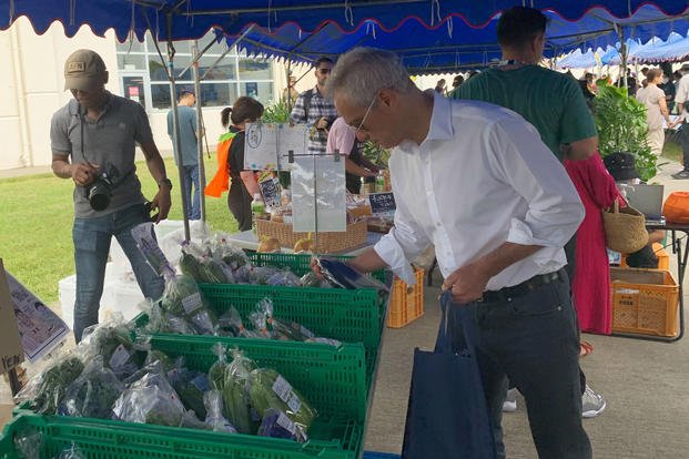 U.S. Ambassador to Japan Rahm Emanuel looks at vegetables at the farmers market at Camp Hansen.