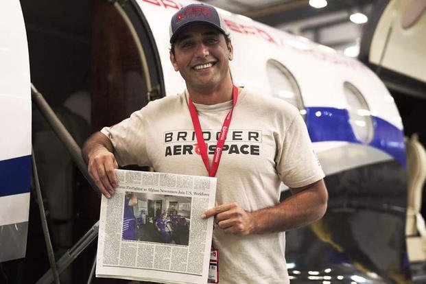 Former Afghan Air Force pilot Samimullah Samim holds up a newspaper chronicling his transition from bombing the Taliban to tracking U.S. forest fires.
