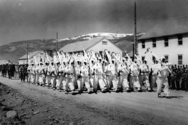 Soldiers of the 10th Mountain Division parade down a street at Camp Hale, Colo., probably in 1943. They are wearing their “whites,” the winter camouflage uniforms, and carry white skis on their right shoulder as rifles are normally carried while on parade. (Photo part of the Western History Collection at the Denver Public Library)