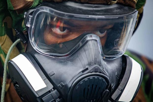 A sailor dons a gas mask in preparation for training.