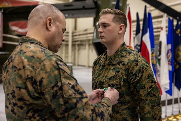 U.S. Marine Corps Cpl. Chase Portello, a noncommissioned officer with Marine Helicopter Squadron One, right, receives a medal from U.S. Marine Corps Col. Carlos Urbina, the director of Command Element Information Division, left, during his award ceremony at Marine Corps Base Quantico, Virginia.