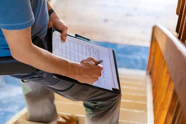 A stock image of a home inspector writing on a clipboard.