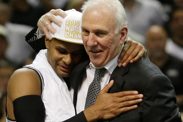 San Antonio Spurs guard Patty Mills (8) and head coach Gregg Popovich embrace after Game 5 of the NBA basketball finals on Sunday, June 15, 2014, in San Antonio. The Spurs won the NBA championship 104-87. (AP Photo/David J. Phillip)