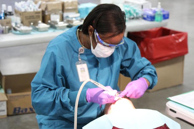 A dental hygienist from the 810th Medical Company in Charleston, S.C., provides dental care for a patient.
