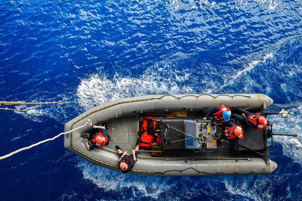 Sailors conduct a small boat exercise alongside the USS Nimitz.