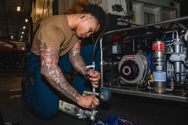 Sailor maintains an emergency breathing air compressor on an carrier.