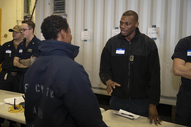 Culinary Specialist 1st Class Brandon Francis speaks with Professional Apprenticeship Career Track (PACT) sailors during a job mentorship fair in the ship’s hangar bay. 
