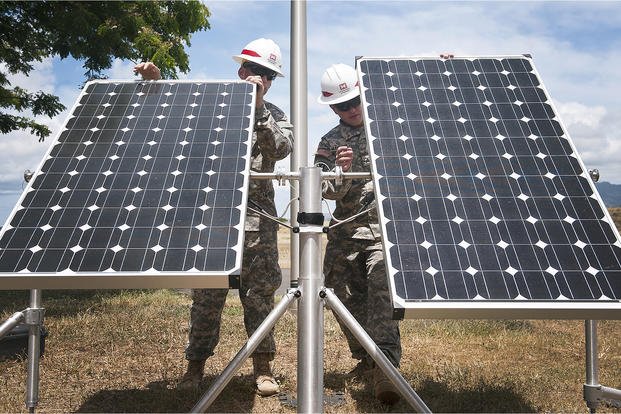 Two prime power production specialists position solar array panels for use during the Rim of the Pacific exercise 2014 at Ford Island, Hawaii. 