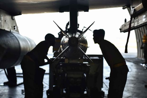 Airmen secure a JDAM onto an F-16 Fighting Falcon.