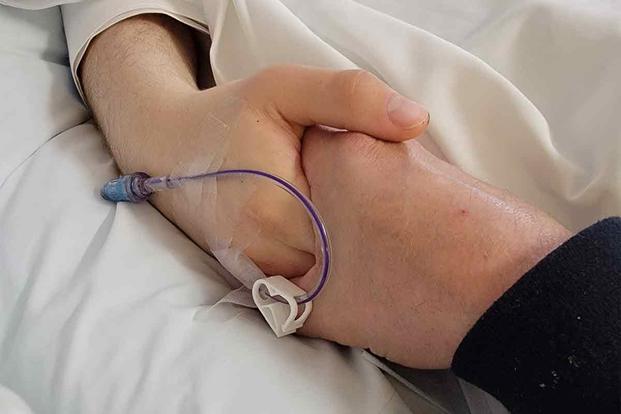 Austin's father holds his hand before he is taken off of life support.