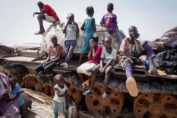 Children sit and play on the remains of a tank, at the river port in Renk, South Sudan.