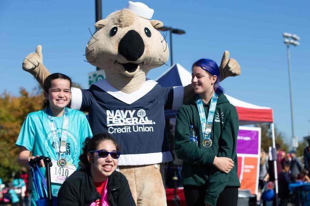 The Navy Federal Credit Union mascot takes a photo with runners.