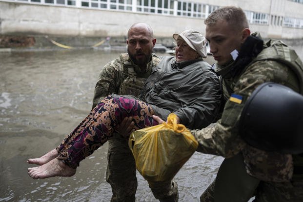 Ukrainian servicemen help rush to safety an injured civilian evacuee