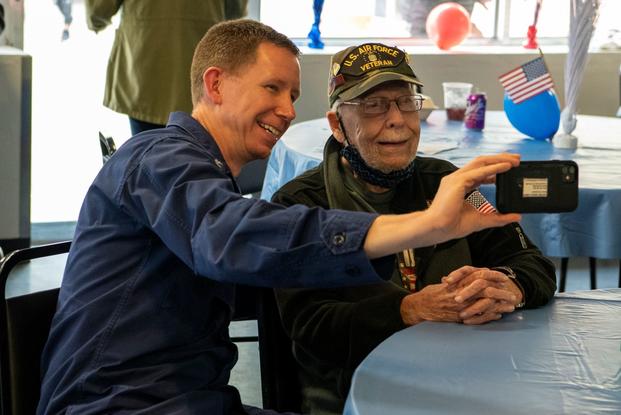Coast Guard officer takes a photo with a veteran at a veterans home in Texas.